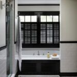 Chic black and white bathroom features a window covered in black .