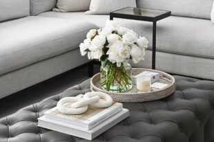 A large black leather tufted ottoman coffee table sits on a light .